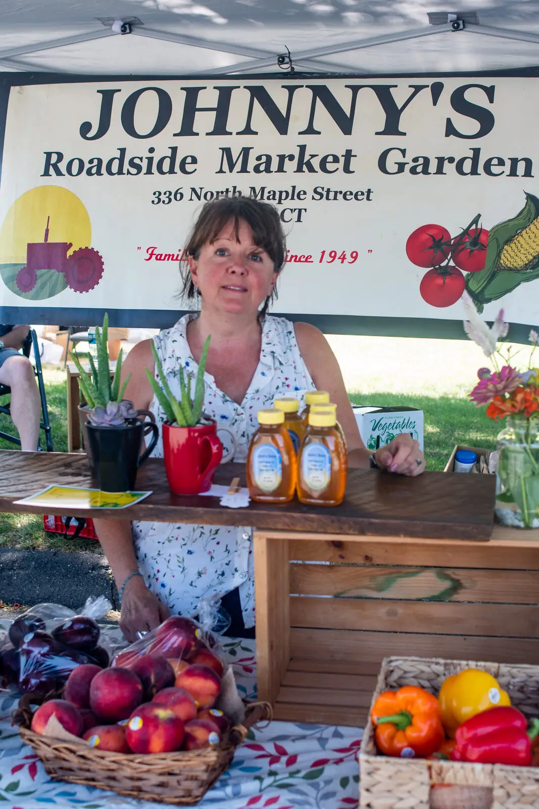 A local grower's stand with peaches, honey and peppers at the Enfield Community Market
